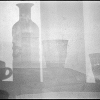 Cup, bottle and glasses on a wall