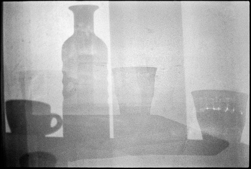 Cup, bottle and glasses on a wall